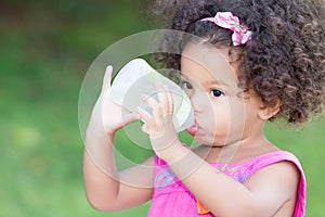 Cute latin girl drinking from a baby bottle