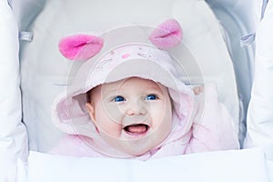 Cute laughing baby girl enjoying a stroller ride