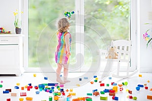 Cute laughing toddler girl playing with colorful blocks