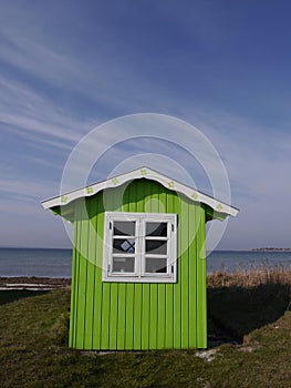 A cute lime-green beach hut with background of blue sea and sky, Aero, Denmark