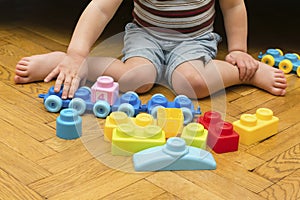 Cute little adorable caucasian boy playing with multi-colored constructor at home. Babys hands building tower of plastic blocks.
