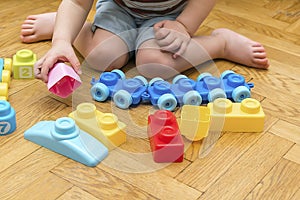 Cute little adorable caucasian boy playing with multi-colored constructor at home. Babys hands building tower of plastic