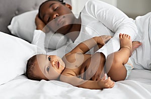 Cute little African American baby sleeping in bed with mom