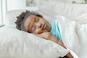 Cute little African American boy child sleeping in bed