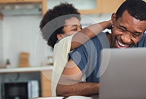 Cute little African American boy hugging and playing with dad while his dad working from home with laptop computer for remoter job