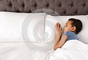 Cute little African-American boy sleeping in bed