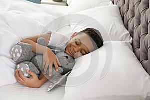 Cute little African-American boy with toy rabbit sleeping