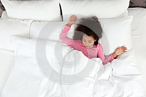 Cute little African-American girl sleeping in bed