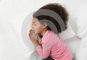 Cute little African-American girl sleeping in bed