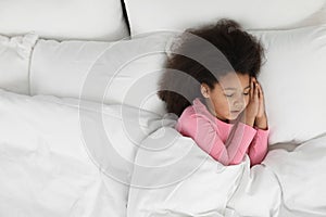 Cute little African-American girl sleeping in bed
