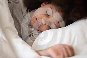 Cute little african american kid girl sleeping alone in bed