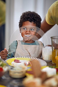 Cute little african boy smiling at table, with milk moustache