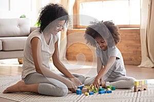 Cute little african kid playing with black mom on floor