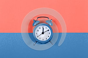 Cute little alarm clock on two colored background - Living Coral and Classic Blue. Color of the year 2020