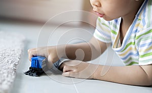 Cute little Asain boy playing with colorful toys on floor at home, space for text