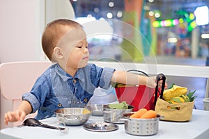 Cute little Asian 18 months / 1 year old toddler baby boy child having fun playing alone with cooking toys at play school / child