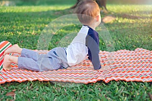 Cute little Asian 18 months / 1 year old toddler baby boy child practices yoga in cobra Pose and meditating outdoors on nature in