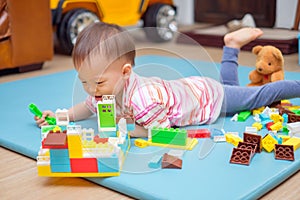 Cute little Asian 18 months / 1 year old toddler boy child having fun playing with colorful building blocks indoor he lay down and