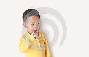 Cute little asian baby boy brushing teeth and looking beside on white background with copy space