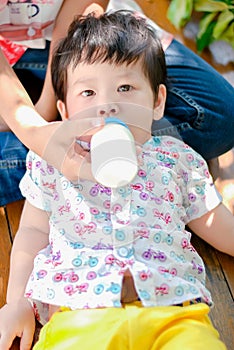 Cute little Asian boy Happy smilling eat milk in the park outdoors , Happy kids