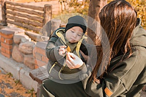 Cute little asian boy with mother outdoors. Happy child walking in autumn park. Toddler baby boy wears trendy jacket and