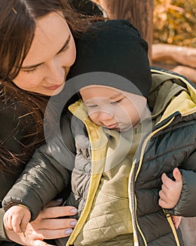 Cute little asian boy stands outdoors close-up. Happy child walking in autumn park. Toddler baby boy wears trendy jacket