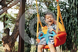 Cute little Asian child boy having fun on swing