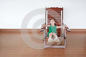 Cute little Asian child girl lying on Thai wooden traditional chair