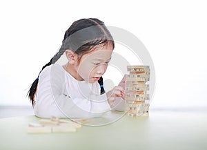 Cute little Asian child girl playing wood blocks tower game for Brain and Physical development skill in a classroom. Focus at