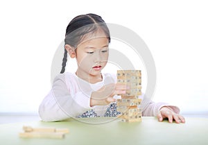 Cute little Asian child girl playing wood blocks tower game for Brain and Physical development skill in a classroom. Focus at