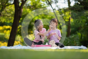 Cute little Asian children eating sweet donuts, tasty food for kids, Funny time in the park