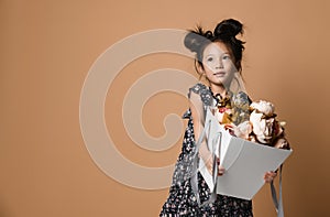 Cute little asian girl in beautiful spring dress holds a big basket of big white flowers pion and looks up at somebody photo