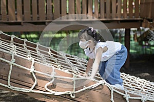 Cute little Asian girl climbing rope net and playing at the playground.