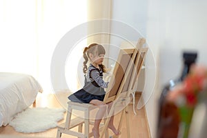 Cute little asian girl drawing on chalkboard in the white room at home, relax and summertime.