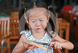 Cute little Asian girl eating bread sheet. Asian girl having breakfast