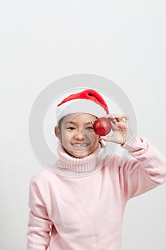 Girl holding a red christmas ball in sweater and santa hat