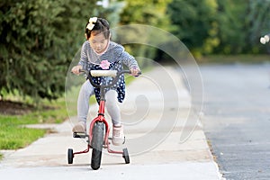 Cute little girl learning ride a bicycle with no helmet