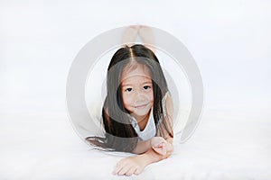 Cute little Asian girl lying on bed with looking at camera over white background