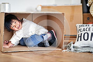 Cute little asian girl playing, hiding in cardboard box