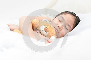 Cute little asian girl sleep and hug teddy bear on bed