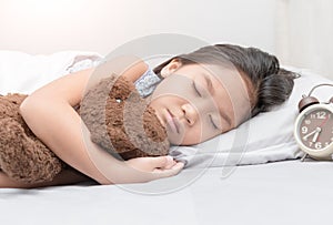 Cute little asian girl sleep and hug teddy bear on bed