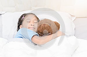 Cute little asian girl sleep and hug teddy bear on bed