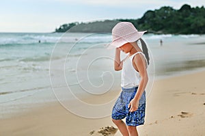 Cute little asian girl wear straw hat walking on the beach