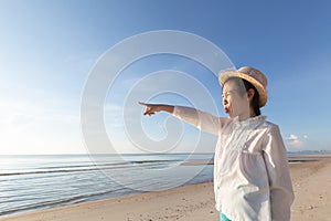 Cute little asian girl wear straw hat walking on the beach with