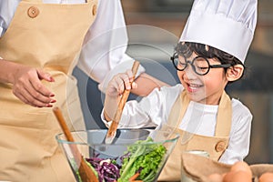 Cute little Asian happy boy interested in cooking with mother funny in home kitchen. People lifestyles and Family. Homemade food