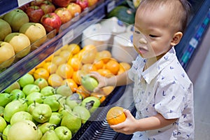 Cute little Asian 18 months / 1 year old toddler baby boy child shopping in a supermarket photo