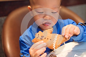 Cute little Asian 2 years old toddler baby boy child eating Gingerbread Man
