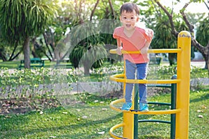 Cute Asian 3 years old toddler baby boy child having fun trying to climb on climbing frame at outdoor playground