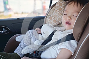 Cute little Asian 2 - 3 years toddler baby boy child sleeping in modern car seat. Child traveling safety on the road