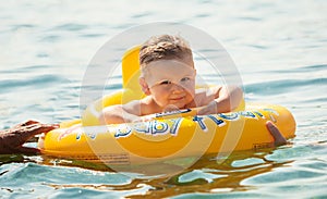 Cute little baby boy in a babies swimming ring, floating in the sea